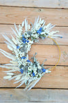 Decorative wreath with dried flowers and blue accents on a wooden surface